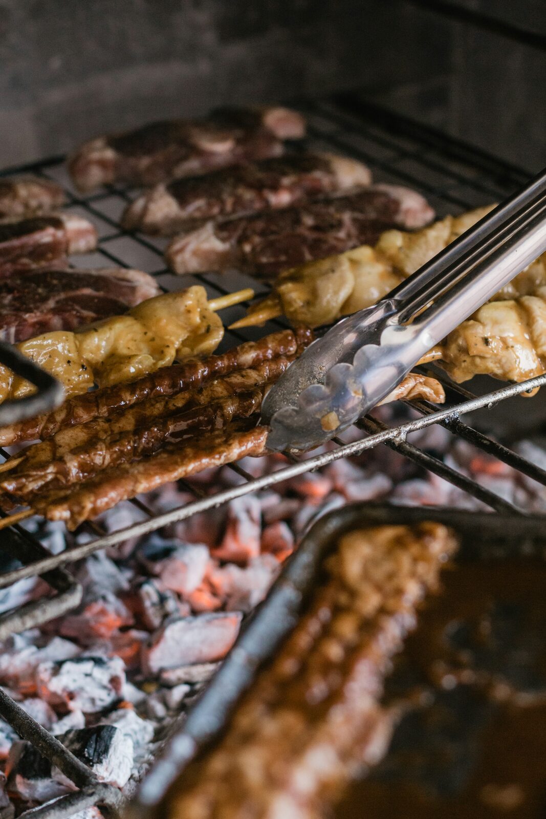 Meat grilling over hot coals on an open braai.